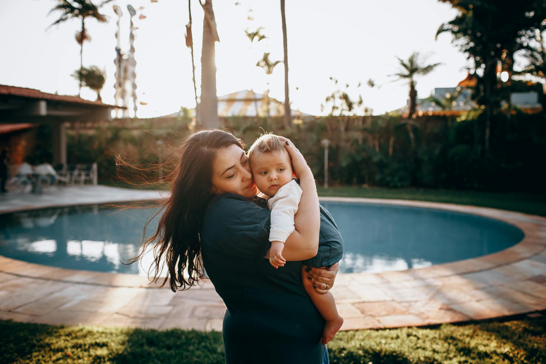 Mama przytula dziecko przy basenie o zachodzie słońca