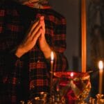 Osoba modląca się przy świecach w ciemnym kościele